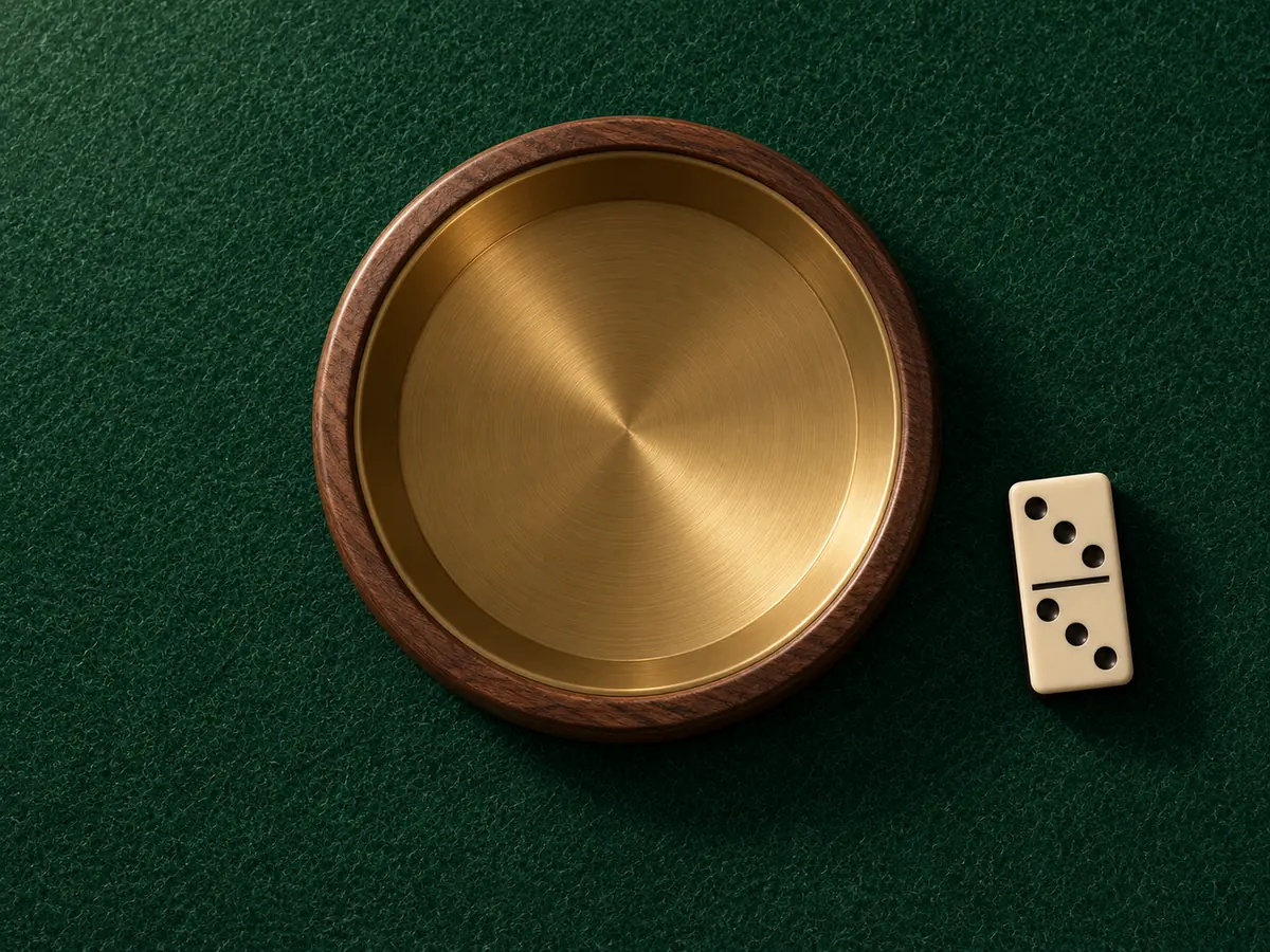 A brass dish in a walnut ring on the felt, one domino beside it